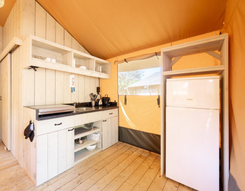 Cucina ben attrezzata con frigorifero nella tenda safari Villatent Nomad, legno chiaro e luce naturale.
