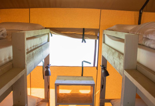 Interno di una tenda safari Villatent Nomad con due letti a castello, mobili in legno e luce naturale.