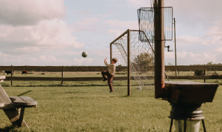 Niño juega al fútbol en un campo verde con portería cerca de Ophemert, Gelderland, Países Bajos.
