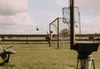 Jongen speelt voetbal bij een doel in een tuin vlakbij Ophemert, Gelderland, Nederland.