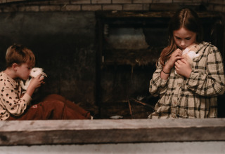 Two children cuddle rabbits in a rustic barn at Feather Down Hoeve De Pippert, Gelderland, Netherlands.