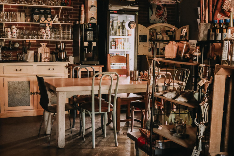 Cozy café interior with wooden tables and mixed chairs at Feather Down Hoeve De Pippert, Gelderland, Netherlands.