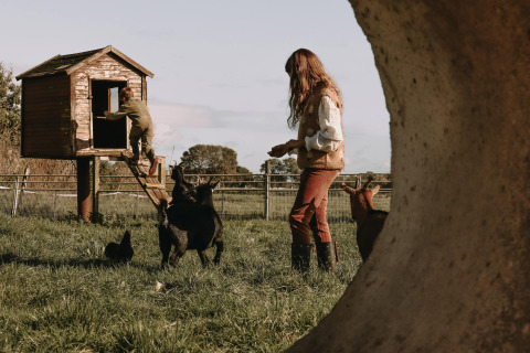 Zwei Personen mit Tieren auf einer Wiese bei einem Baumhaus nahe Ophemert, Gelderland, Niederlande.