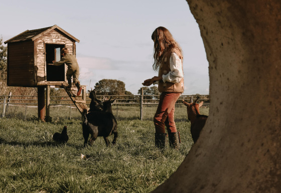 Dos personas con cabras y gallinas junto a una casita en un campo verde en Ophemert, Gelderland, Países Bajos.