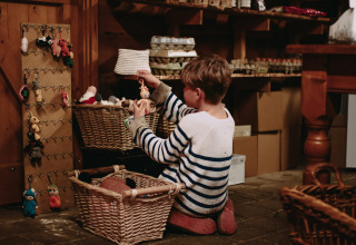 Et barn i en stribet sweater leger med hæklede nøgleringe i en hyggelig, rustik butik på Hoeve De Pippert.