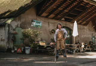 Barn leger på stylter foran en rustik bygning ved Feather Down Hoeve De Pippert, feriepark i Gelderland, Holland.