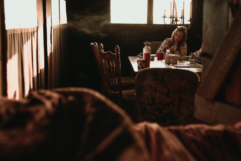 Woman sits at a table in a sunlit cabin at Feather Down Hoeve De Pippert holiday park in Gelderland, Netherlands.