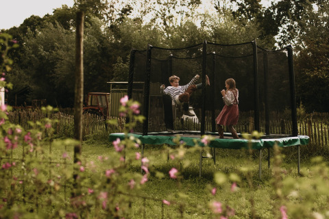To børn leger på en trampolin i en have med blomster ved Feather Down Hoeve De Pippert, Gelderland, Holland.