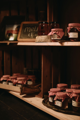 Shelves with homemade jam and honey in jars with red checkered lids at Feather Down Hoeve De Pippert.