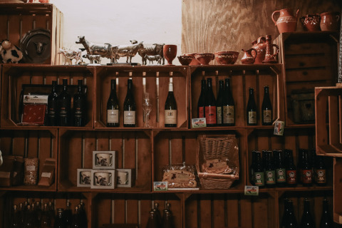 Estantes con botellas de vino, cerámica y productos locales en Feather Down Hoeve De Pippert, Gelderland.