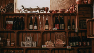 Estantes con botellas de vino, cerámica y productos locales en Feather Down Hoeve De Pippert, Gelderland.
