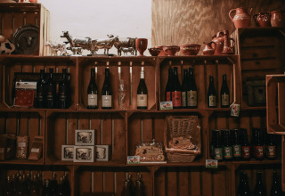 Étagères avec bouteilles de vin, céramique et produits locaux chez Feather Down Hoeve De Pippert, Gelderland.