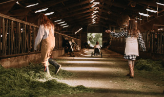 Niños juegan en un granero con heno fresco en Feather Down Hoeve De Pippert, parque vacacional en Gelderland, Países Bajos.