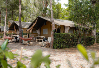 Tienda safari Villatent Nomad en Camping Casa dei Prati, Italia, rodeada de árboles y áreas de descanso.