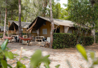 Tienda safari Villatent Nomad en Camping Casa dei Prati, Italia, rodeada de árboles y áreas de descanso.
