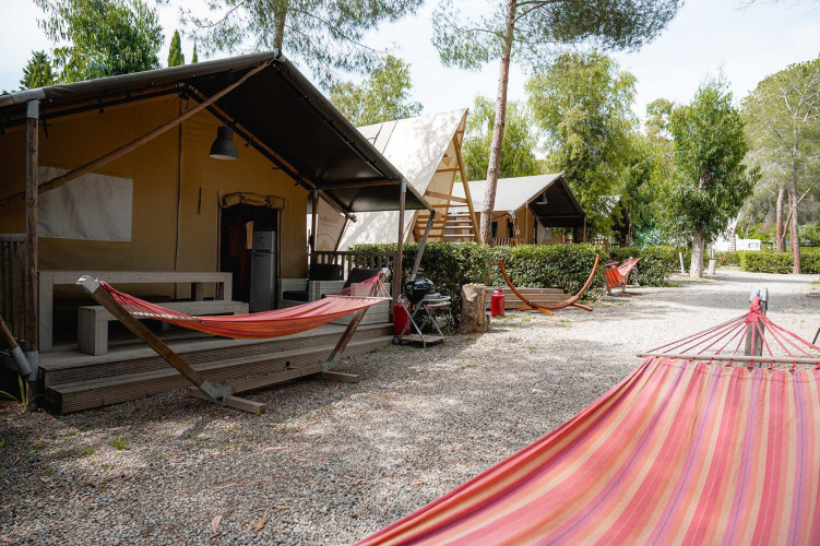 Tienda safari Villatent Nomad en Camping Casa dei Prati, Italia, con hamacas y árboles alrededor.