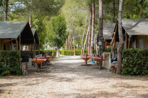 Safaritenten bij Camping Casa dei Prati in Italië, met hangmatten en bomen in een rustige omgeving.
