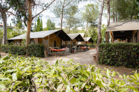 Safaritenten Villatent Nomad op Camping Casa dei Prati in Italië, tussen bomen, hangmatten en groene hagen.