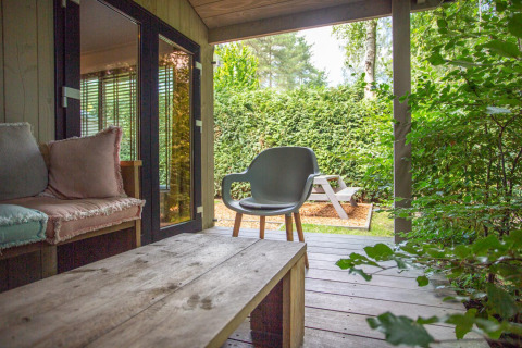 Gezellige veranda bij Boslodge op De Thijmse Berg in Nederland, met zitruimte en tuinzicht.