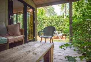 Veranda accogliente alla Boslodge di De Thijmse Berg nei Paesi Bassi con sedute e vista verde.