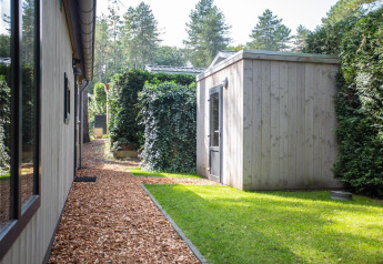Udsigt over gangsti og græsplæne ved hytter i Boslodge på De Thijmse Berg, Holland, omringet af træer