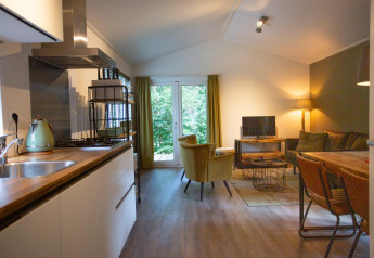 Hyggelig stue og køkken i Boslodge på De Thijmse Berg, Holland, med moderne indretning og store vinduer.