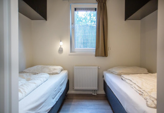Camera da letto alla Boslodge presso De Thijmse Berg, Paesi Bassi, con due letti singoli e finestra centrale.