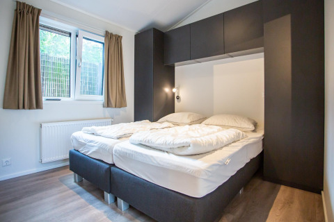 Dormitorio moderno con dos camas, grandes ventanas y armarios en Boslodge, De Thijmse Berg, en los Países Bajos.