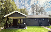 Bos Cottage Deluxe bij De Thijmse Berg, Nederland; houten lodge met overdekte veranda en bosrijke omgeving.