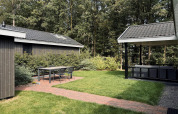 Patio accogliente con tavolo e sedie al Bos Cottage Deluxe di De Thijmse Berg, circondato dal verde nei Paesi Bassi.