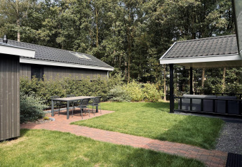 En hyggelig terrasse med bord og stole ved Bos Cottage Deluxe på De Thijmse Berg, omgivet af grønt i Holland.