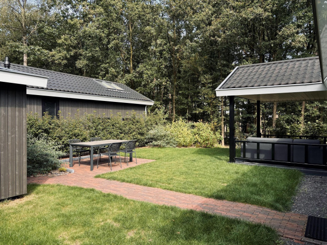 Acogedora terraza con mesa y sillas en Bos Cottage Deluxe de De Thijmse Berg, rodeada de vegetación en Países Bajos.