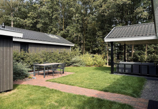 Gemütliche Terrasse mit Tisch und Stühlen bei Bos Cottage Deluxe auf De Thijmse Berg, umgeben von Natur in den Niederlanden.