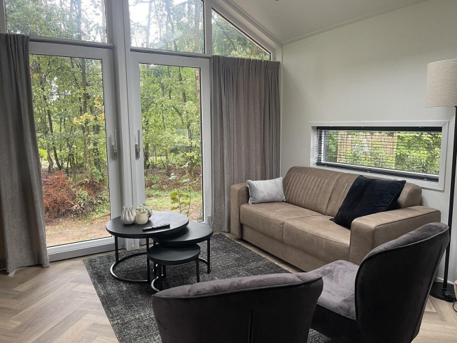 Living room at Bos Cottage Deluxe, De Thijmse Berg, Netherlands, featuring large windows and modern decor.
