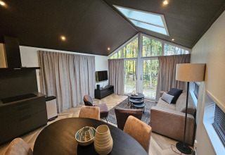 Moderna cabaña Bos Cottage Deluxe en De Thijmse Berg, Países Bajos, con grandes ventanales y decoración acogedora.