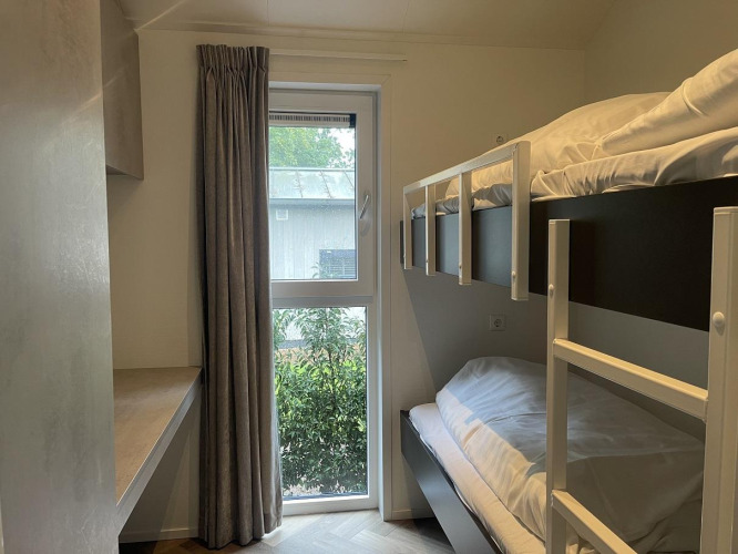 Chambre moderne avec lits superposés et fenêtre, prise au Bos Cottage Deluxe, De Thijmse Berg, Pays-Bas.