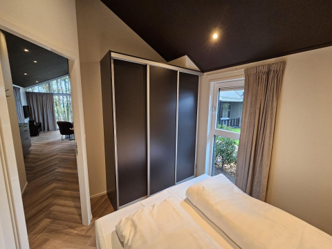 Dormitorio en Bos Cottage Deluxe en De Thijmse Berg, Países Bajos, con armario moderno y vista al jardín.