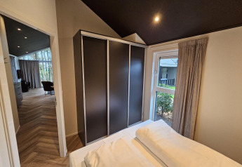 Schlafzimmer in der Bos Cottage Deluxe im De Thijmse Berg, Niederlande, mit Fensterblick und Schrank.
