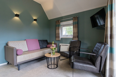 Moderne Wohnzimmer in der Vechtdallodge, Kampeerdorp de Zandstuve, mit Sofa, Sesseln und Couchtisch.