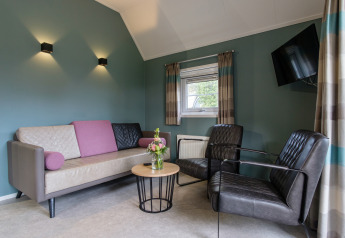 Moderne Wohnzimmer in der Vechtdallodge, Kampeerdorp de Zandstuve, mit Sofa, Sesseln und Couchtisch.