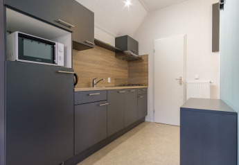 Moderne Küchenzeile in einer Vechtdallodge, Kampeerdorp de Zandstuve, Niederlande, mit grauen Schränken.