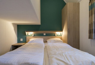 Gemütliches Schlafzimmer in der Vechtdallodge, Kampeerdorp de Zandstuve, mit zwei Einzelbetten und grünem Akzent.