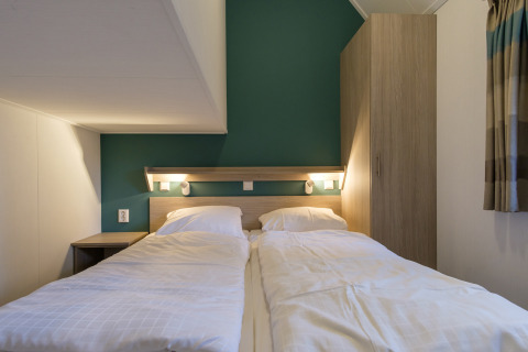 Dormitorio acogedor en Vechtdallodge, Kampeerdorp de Zandstuve, Países Bajos, con camas gemelas y pared verde.