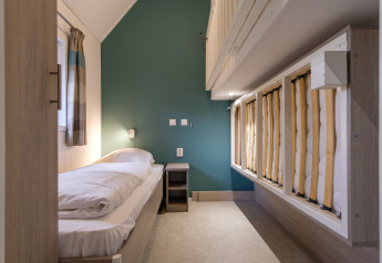 Moderne slaapkamer in Vechtdallodge bij Kampeerdorp de Zandstuve, Nederland, met eenpersoonsbedden en groene muur.