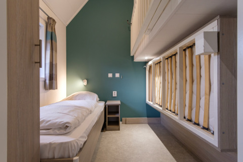 Dormitorio moderno en Vechtdallodge, Kampeerdorp de Zandstuve, Países Bajos, con camas individuales y pared verde.