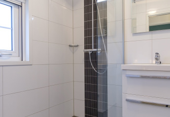 Modernes Badezimmer mit Dusche, Glaswand, weißem Waschbecken und Fenster in der Vechtdallodge, Niederlande.