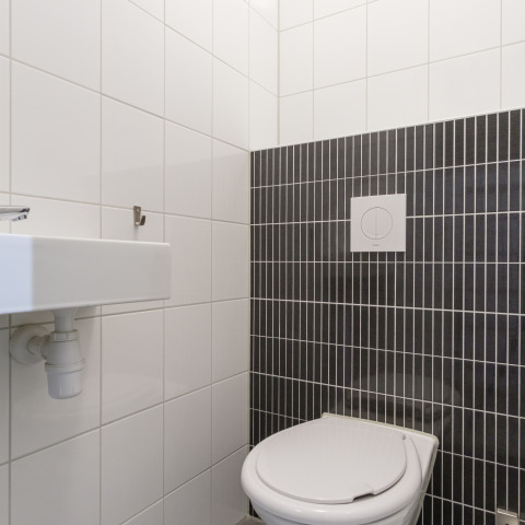 Moderne toilet og håndvask med hvide og mørke fliser i Vechtdallodge, Kampeerdorp de Zandstuve, Holland.