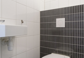 Modernes WC mit weißen und dunklen Fliesen, fotografiert in der Vechtdallodge im Kampeerdorp de Zandstuve, Niederlande.