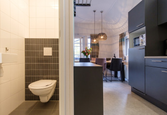 Interno di una moderna lodge con bagno, cucina e zona pranzo a Vechtdallodge, Kampeerdorp de Zandstuve, Paesi Bassi.