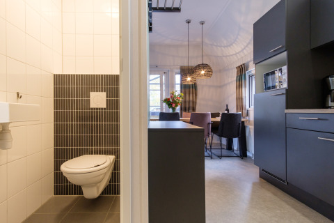 Interior moderno de una cabaña con baño, cocina y comedor en Vechtdallodge, Kampeerdorp de Zandstuve, Países Bajos.